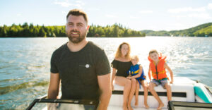 Man driving boat on holiday with his son kids and his wife